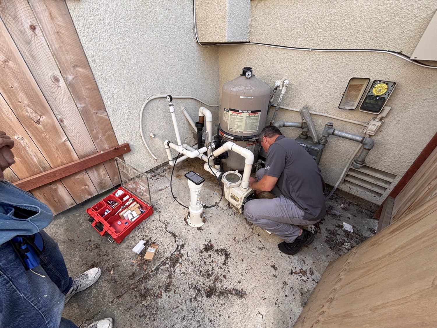 A technician servicing pool equipment — filter, pump and valves — at a customer’s home