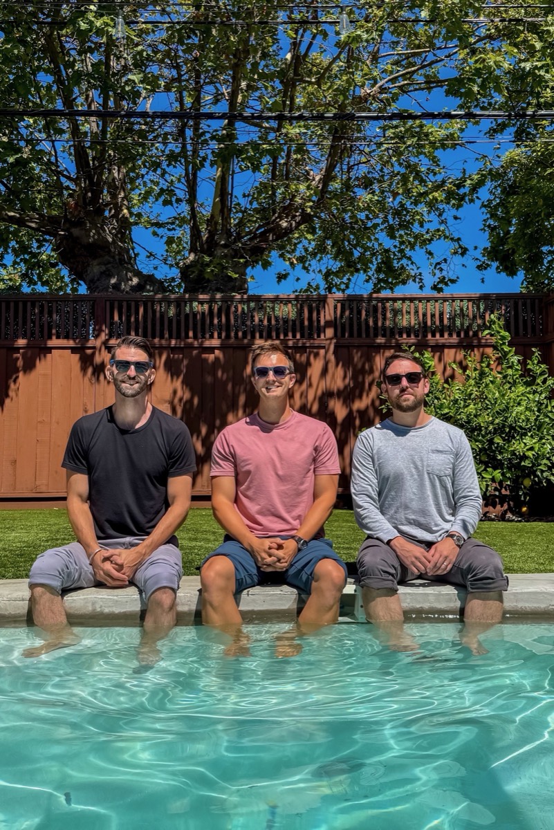 Evan Ferl, Eric Johnston and Mark Doody sitting at the edge of a pool