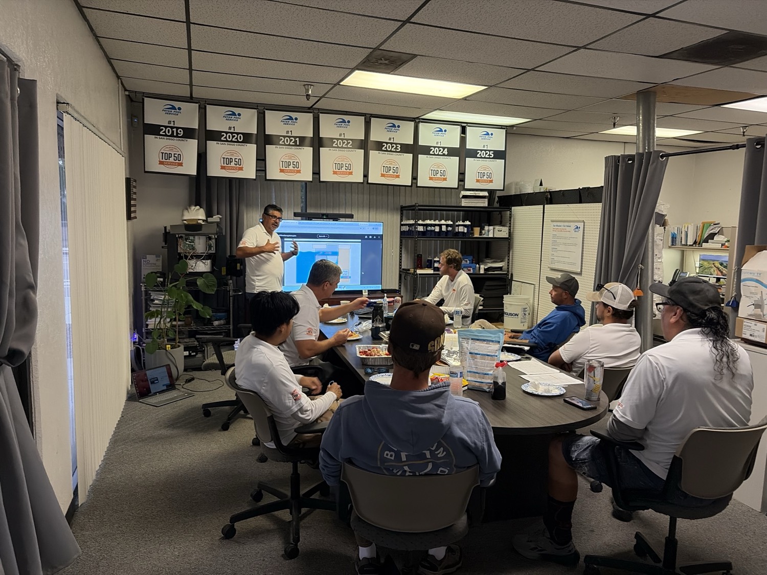 A Payan Pool Service team meeting in San Diego, beneath the company’s Top 50 Service awards